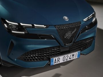 Close-up van de grille en koplampen van een blauwe Alfa Romeo met een Europees kenteken.