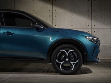 Blue-green Alfa Romeo MILANO luxury SUV parked in a modern concrete garage, highlighting the design of the alloy wheels.