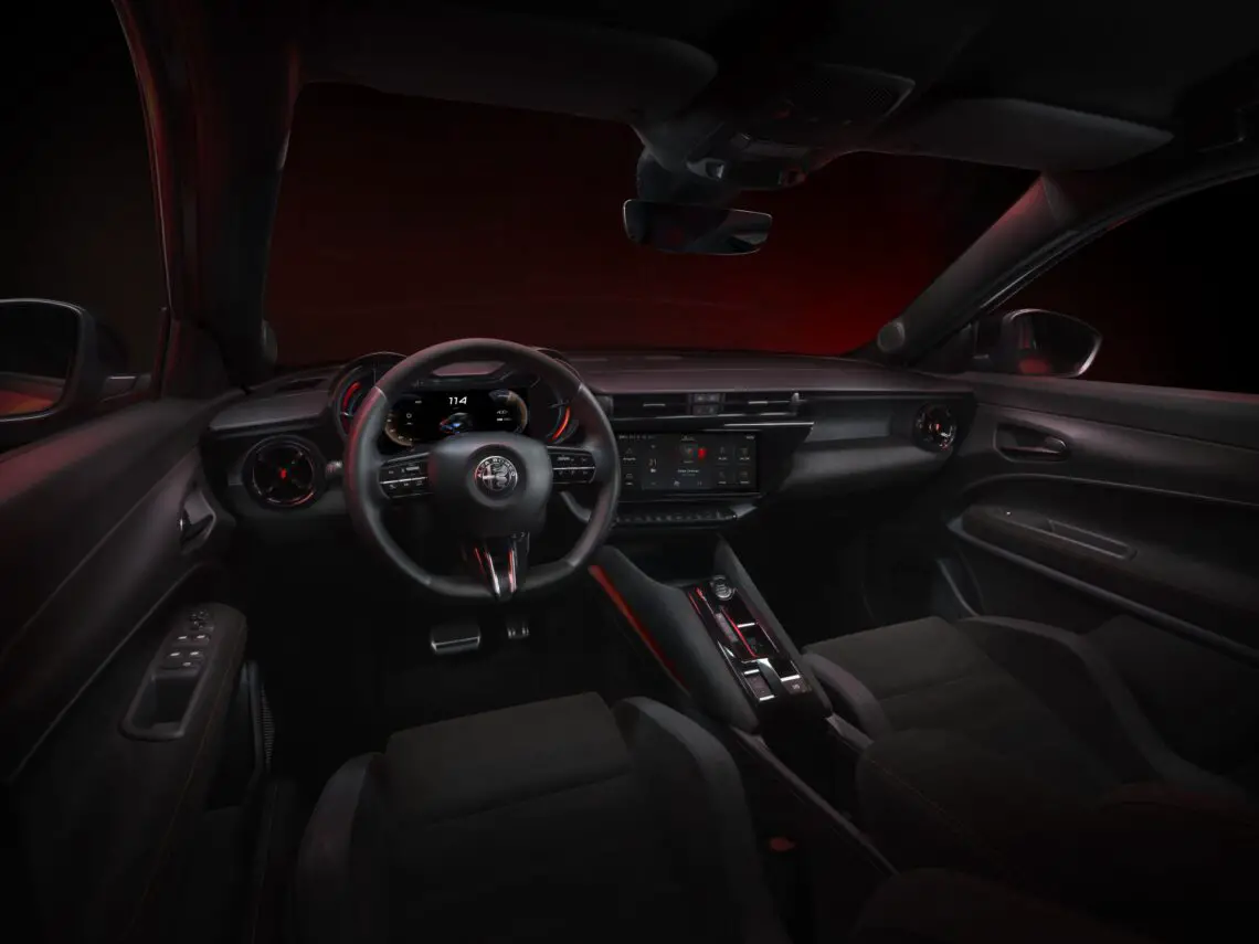 Interior of a modern Alfa Romeo Milano showing the steering wheel, dashboard and center console with red ambient lighting.