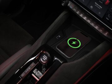 Un smartphone qui se recharge sans fil dans la console centrale d'une Alfa Romeo MILANO moderne.