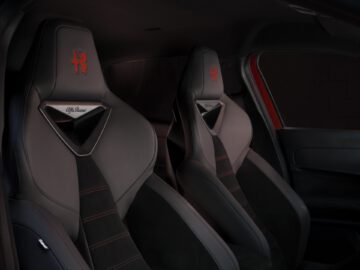 Sportwageninterieur met luxe zwart en rood gestikte stoelen met het Alfa Romeo MILANO-logo.