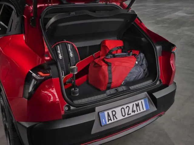 Red duffel bag in the trunk of a red Alfa Romeo Milano with the trunk door open.