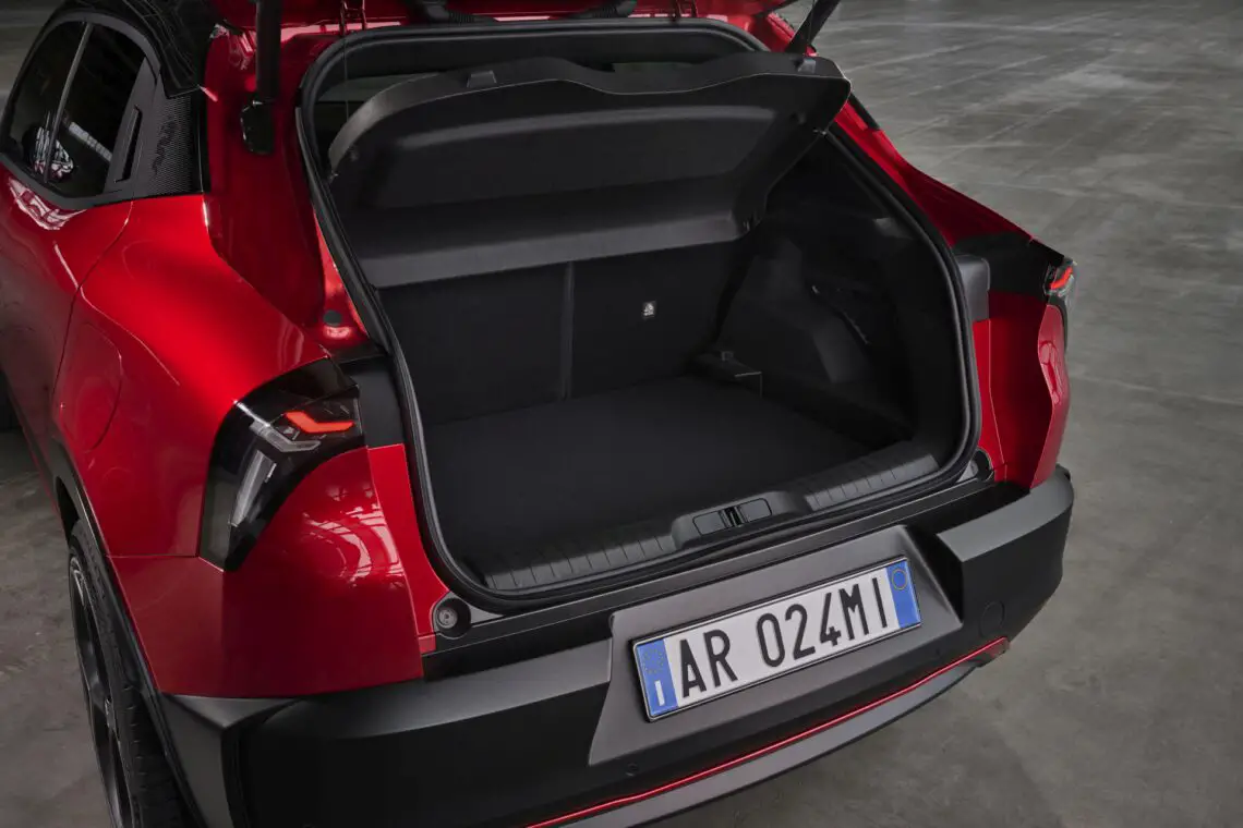 Red Alfa Romeo Milano hatchback with open trunk showing the cargo area.