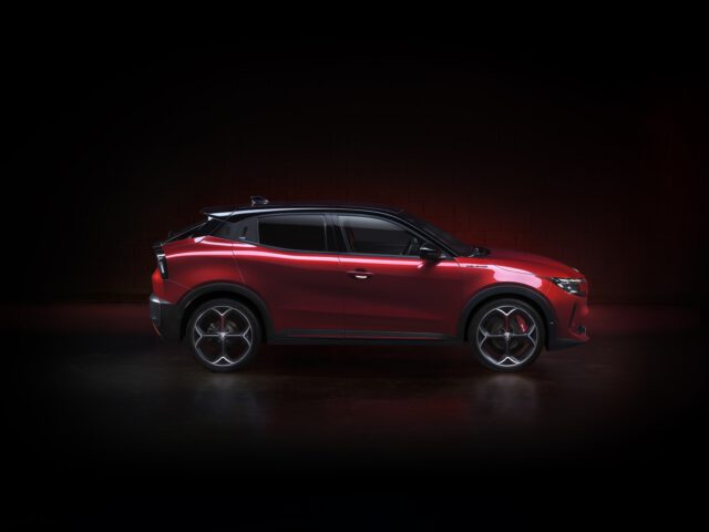Rode Alfa Romeo SUV in een donkere studioomgeving met spotlight die het ontwerp benadrukt.