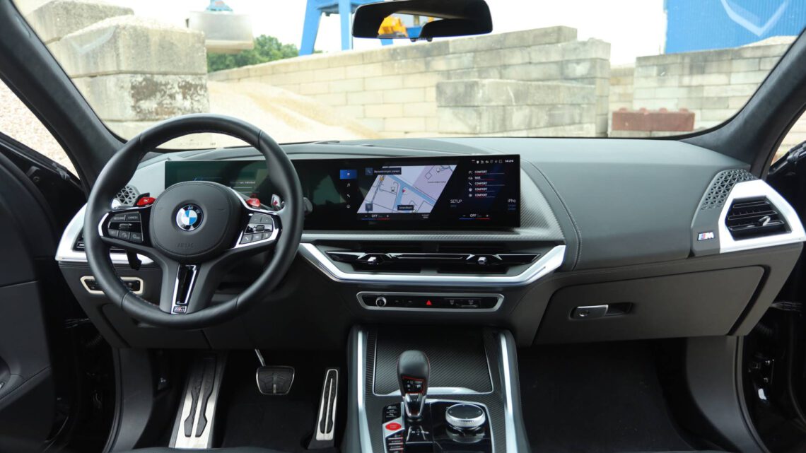 Vue de l'intérieur de la BMW XM montrant le volant, le tableau de bord avec l'affichage numérique et la console centrale.