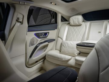 Binnenaanzicht van een Mercedes-Benz EQS met gedetailleerde lederen stoelen, stijlvolle deurpanelen en sfeerverlichting.