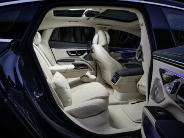 Interior of a Mercedes-Benz EQS, with spacious rear seats fitted with cream leather upholstery and modern design elements.