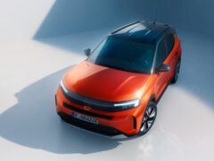 Oranje Opel Frontera geparkeerd onder diffuus licht.