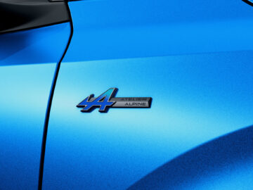 Close-up van het zijpaneel van een blauwe auto met een badge met het nummer 44 en de tekst 'Atelier Alpine', een verwijzing naar de krachtige Fransoos-techniek.