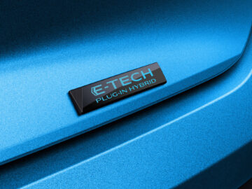Close-up van een blauwe auto met een "E-Tech Plug-In Hybrid"-embleem op de achterkant, dat doet denken aan de krachtige Fransoos-stijl.