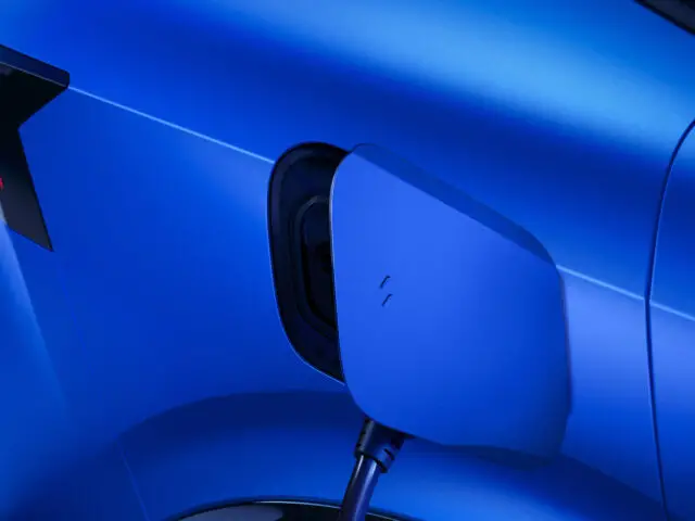 Close-up van een E-Tech 4×4 elektrische auto die wordt opgeladen, waarbij de kabel is aangesloten op de oplaadpoort van een blauw voertuig.