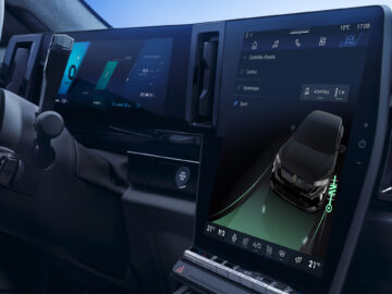 Binnenaanzicht van een Renault Rafale-dashboard met twee grote digitale displays die navigatie- en voertuigcontrole-informatie weergeven. Het stuur en een deel van de bestuurdersdeur zijn ook zichtbaar, wat de baanbrekende E-Tech 4x4-technologie benadrukt.