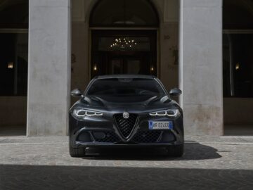 Voor de ingang van een gebouw staat tussen twee kolommen een Alfa Romeo met kenteken "AR 020CQ" geparkeerd.