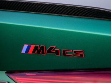 Close-up van een groene BMW-auto met het modelbadge "M4 CS" met een rode, blauwe en witte streep.