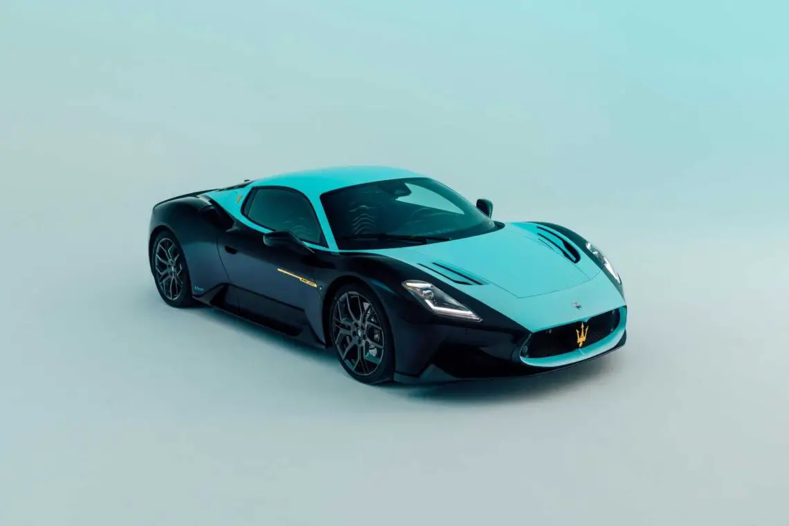 Een strakke zwart-turquoise Maserati MC12-sportwagen is gepositioneerd op een lichtblauwe achtergrond en laat zijn moderne design en aerodynamische vorm zien.