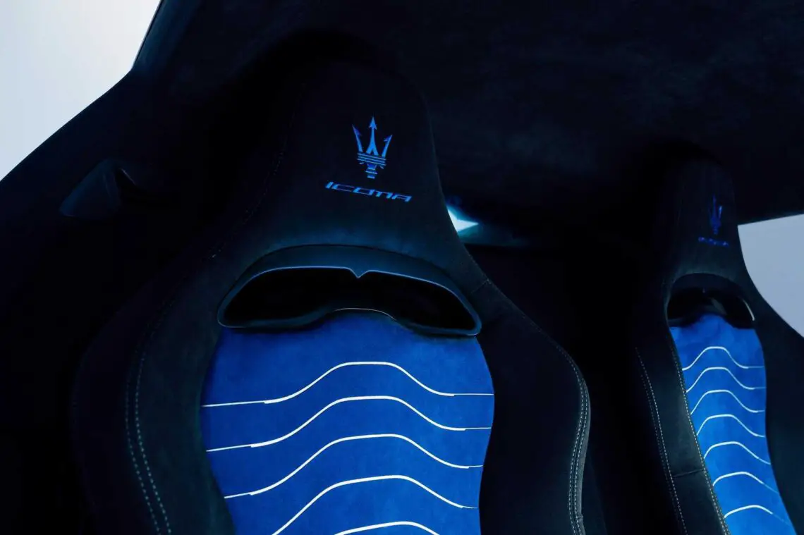 Close-up van blauwe en zwarte autostoelen met het Maserati-logo en 'Icona'-tekst geborduurd op de hoofdsteunen, die doen denken aan de luxueuze interieurs van modellen als de MC12.