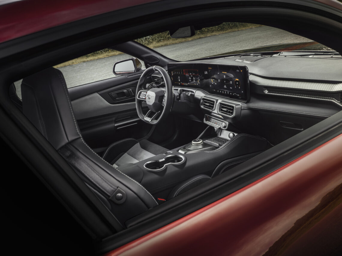 Das Interieur des Ford Mustang GTD verfügt über ein lederummanteltes Lenkrad, ein digitales Armaturenbrett, einen zentralen Infotainment-Bildschirm und schwarze Ledersitze. Das Design ist schlank und modern.