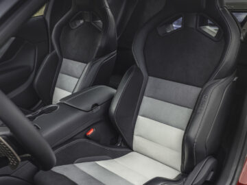 Interior of a Ford Mustang GTD with two black and gray sport seats with prominent stitching and supportive reinforcements, a center console with cup holders next to it.