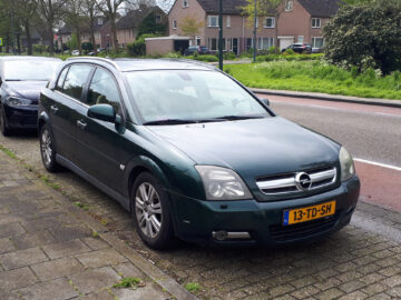 Er werd een groene Opel Signum stationwagen gespot, geparkeerd in een woonstraat met huizen op de achtergrond. De auto heeft een Nederlands kenteken met de tekst "13-TD-SH".