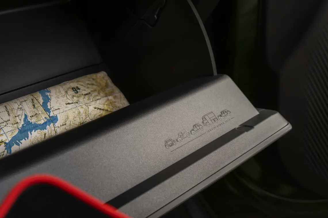 Een close-up van een open dashboardkastje in de Citroën (ë)-C3 Aircross met daarin een kaart. De coupédeur heeft een reliëfontwerp met verschillende voertuigiconen, ideaal voor een zevenzitter-avontuur.
