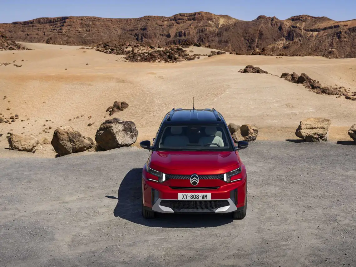 Een rode Citroën C5 Aircross, die de ruige geest van de ë-C3 Aircross oproept, staat geparkeerd in een rotsachtig woestijnlandschap met zand en heuvels op de achtergrond. Van voren gezien luidt het kenteken XT-808-WM.