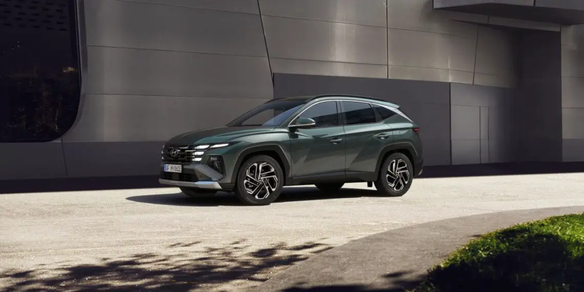 A dark green Tucson SUV parked on a light-colored surface in front of a modern building with metallic gray exterior walls.