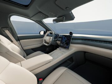 Innenraum eines modernen Autos mit beigen Ledersitzen, einem eleganten Armaturenbrett mit großem Touchscreen und einem Panorama-Schiebedach.