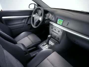 Der Innenraum des modernen Opel Signum bietet schwarze Sitze, einen Schalthebel, Bedienelemente auf dem Armaturenbrett und einen kleinen Navigationsbildschirm mit einer Karte. Aufgefallen durch sein schlankes Design und seine fortschrittliche Technologie.