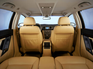 Vue de l'intérieur d'une voiture, avec des sièges en cuir beige, un tableau de bord moderne, un volant et une console centrale avec climatisation et écran : caractéristiques classiques de la Vauxhall Signum Spotted.
