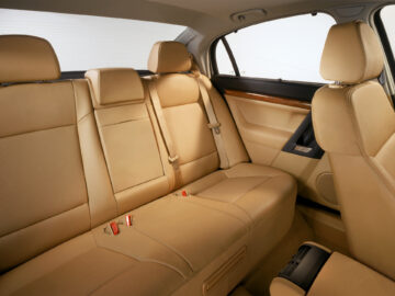 Interior de cuero beige de un Opel Signum con asientos traseros, cinturones de seguridad, molduras de madera en las puertas y reposabrazos central, visto en perfecto estado.