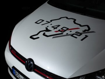 Front view of the hood of a white Volkswagen Golfs with an image of a race track and the numbers 