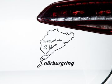 Close-up of a white car with a Nürburgring circuit sticker, with a handwritten lap time 