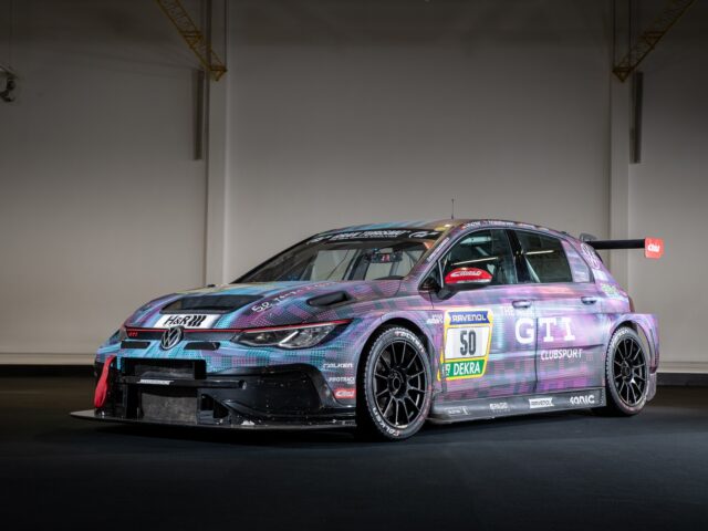 A race car with the number 50 on the side, a multicolored design and various sponsor logos, is parked inside on a dark background. The vibrant colors and clean lines create an impressive scene that seems straight out of a motorsports report.