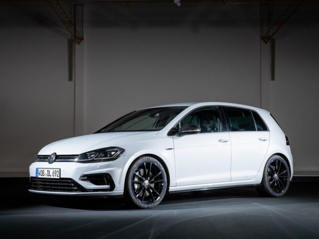 A white Volkswagen Golf GTI with black rims parked in a dimly lit interior.