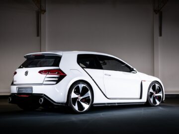 A white Volkswagen Golf GTI Vision sports car is parked inside, showing off its sleek design and striking alloy wheels.