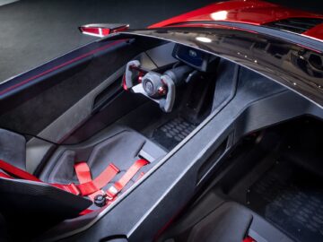 Top view of the minimalist interior of a Volkswagen Golf with two racing seats with red harnesses, a racing-style steering wheel and a center console.