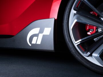 Close-up of the rear wheel of a red sports car and a carbon fiber panel with a white logo with a stylized 