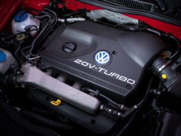 Close-up of a Volkswagen Golf 20V turbo engine in a vehicle, with various components including hoses, cables and fluid reservoirs.