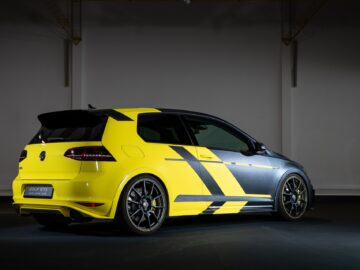 Im Innenraum ist ein gelb-schwarzer Volkswagen Golf GTI geparkt. Der Wagen ist mit sportlichen Emblemen, maßgefertigten Rädern und einem Spoiler ausgestattet und verkörpert so das schnittige Design eines klassischen Volkswagen Golf.