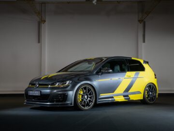 A customized Volkswagen Golf with a black-and-yellow paint job, sporty emblems and alloy wheels is displayed in a showroom.