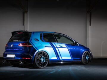 Inside, a blue Volkswagen Golf GTI is parked with custom racing graphics and black alloy wheels. The Volkswagen Golf is seen from the rear and side corners.