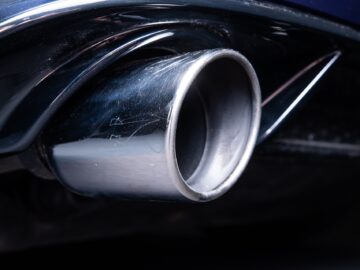 Close-up of the exhaust pipe of a Volkswagen Golf showing a metal, lightly abraded surface with a dark, circular opening.