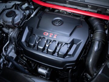 Close-up of the engine compartment of a Volkswagen Golf GTI, with the hood with the VW emblem and the inscription 