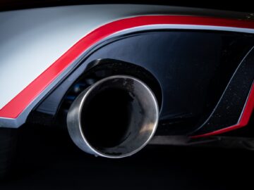 Close-up of the rear exhaust pipe of a Volkswagen Golf, focusing on the metal exhaust. The car features red and white paint with aerodynamic design elements.