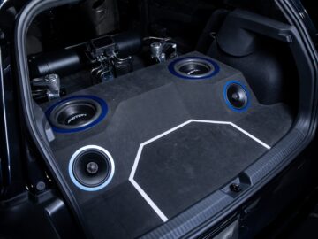 Een Volkswagen Golf-kofferbak, op maat gemaakt met een subwoofer en een geluidssysteem, met meerdere luidsprekers en versterkers geïntegreerd in het ontwerp.