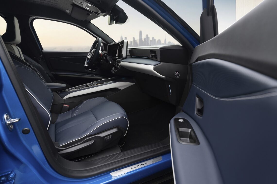 Binnenaanzicht van een moderne blauwe Renault 5 met leren stoelen, een digitaal dashboard en de skyline van de stad zichtbaar door de ramen.