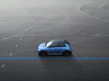 Een blauwe compacte SUV staat geparkeerd op een grote open plek met meerdere elkaar kruisende witte en blauwe lijnen op het asfalt, niet ver van een Alpine A290.