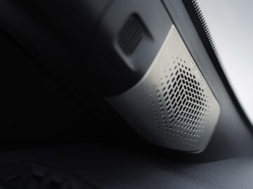 Close-up van een autoluidspreker in het interieur die is geïntegreerd in het dashboard van de Renault 5, met een geperforeerd grille-ontwerp.