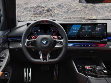 Inside view of a modern BMW dashboard with a digital instrument panel, central infotainment screen and multifunction steering wheel with red and silver accents.