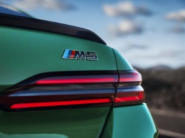 Primer plano de la parte trasera de un BMW M5 verde, mostrando el emblema 